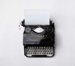 Overhead black and white shot of an old black typewriter with paper in it